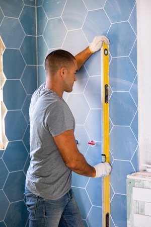 Bathroom remodeling professional using a level during shower and bathtub renovation